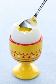 Closeup of soft boiled egg in cup with spoon