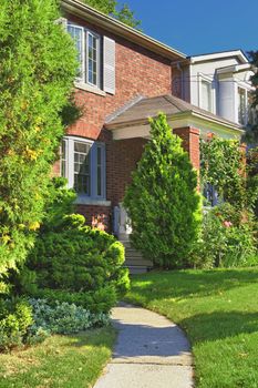 City home in red brick exterior with garden and path