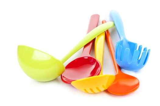 Various colorful plastic kitchen utensils on white background