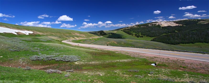 Panorama of a winding road through high elevations of the Bighorn National Forest in Wyoming.