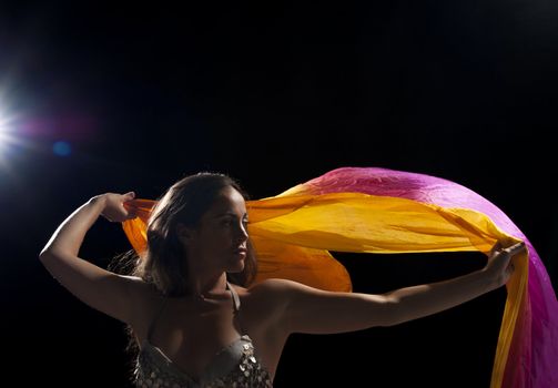 Dancer waving a colorful oriental headscarf, backlit studio shot