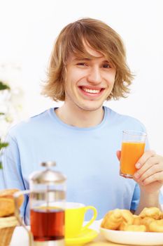 Young happy man smiling and drinking juice