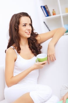 Young pretty woman in white at home sitting on the sofa