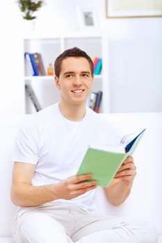 Young handsome man at home with a book