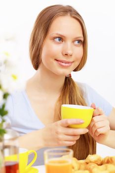 Beautiful young woman drinking tea from yellow cup