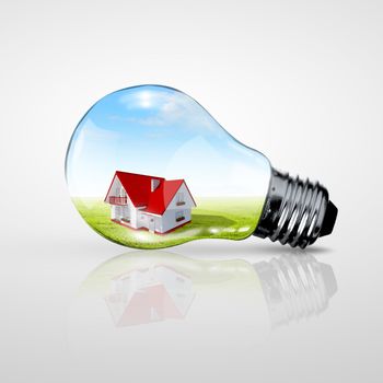 Electric light bulb and house inside it as symbol of green energy