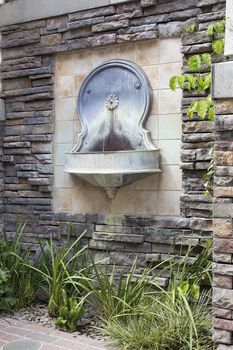 Tuscan Style Wall Water Fountain on Formal Courtyard Garden with Landscaping Plants