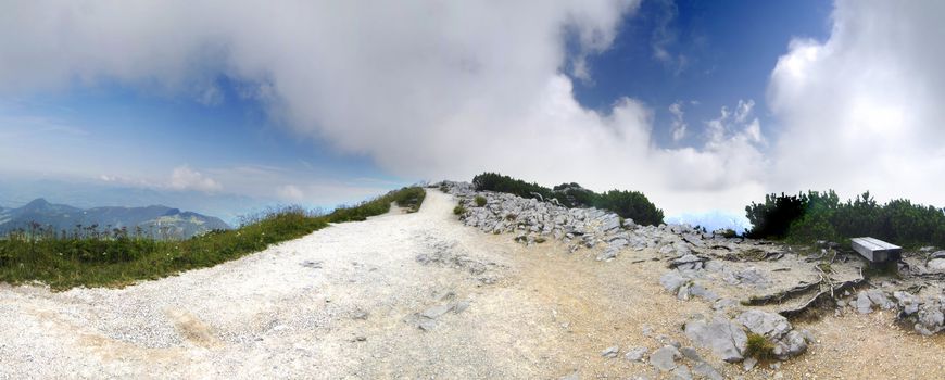 Panoramic picture of the path on one of the alpine peaks hidden in the clouds