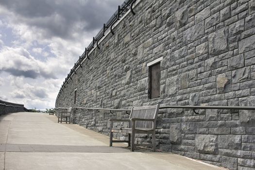 Wooden Benches Along Stone Rock Wall of Public Park Walkway