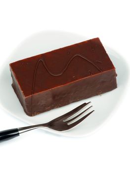 Creamy Mousse Cake Glazed with Dark Chocolate on White Plate with Dessert Fork closeup