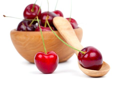 red cherry in wooden spoon and bowl, isolated on white background