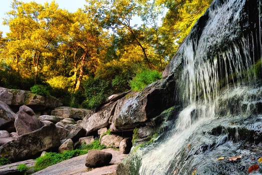 Falls among the rocks and trees in autumn park