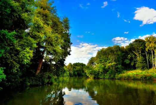 The river among the green shores of summer sunny day