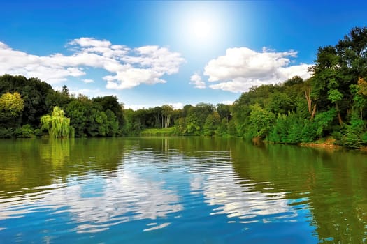 Lake in the forest under a blue sky with bright sunshine