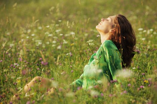 Young beautiful woman enjoying nature in the flowers field