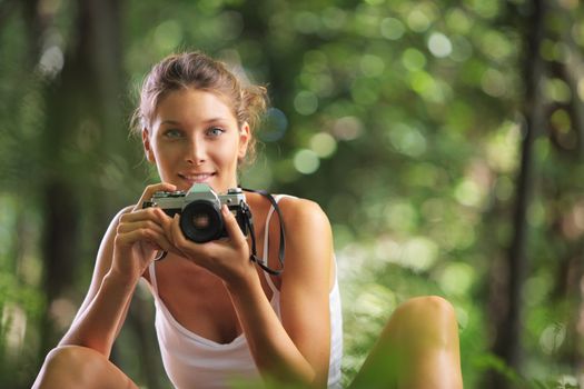 Beautiful woman in the woods with vintage camera