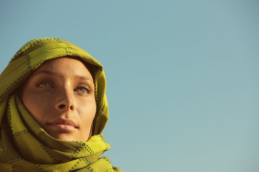 Portrait of woman with a green turban against blue sky, copy space