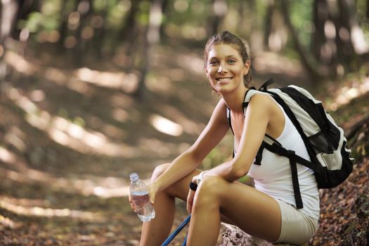 Smiling woman with walking sticks in a forest, having a break