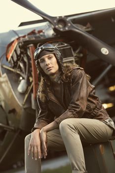 Portrait of young woman airplane pilot. Airplane on the background