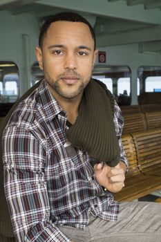 Young black man with sweater held over his shoulder looks into the camera with no smile.