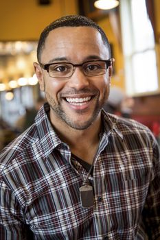 Portrait of smiling young black man in the interior of coffee shop.