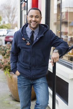 Black man standing in the street leaning of a railing and looking straight into the camera.