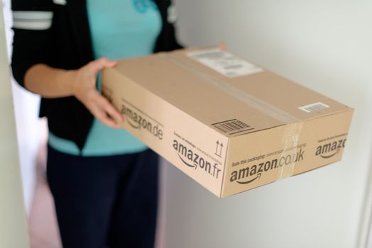 STUTTGART - SEPTEMBER 2: Woman picking up a parcel by Amazon.com in front of her flat on September 2, 2012 in Stuttgart, Germany. Amazon.com is delivering thousands of parcels every day to German households.
