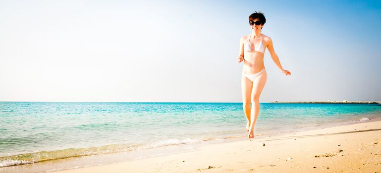 beautiful girl in a white bikini running on the beach
