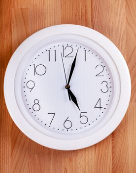 White clock hanging on a wooden wall