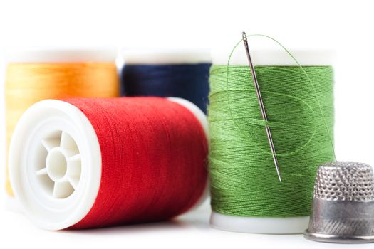 Spools with green, yellow, red and blue threads and needle