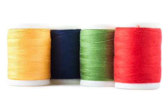 Four spools with green, yellow, blue and red threads