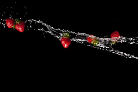 water splash with ripe red strawberry over black background