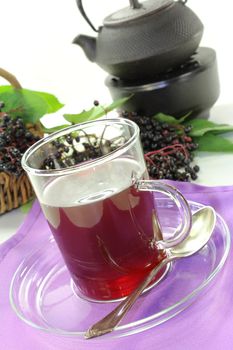 a glass of elderberry tea with fresh elderberries