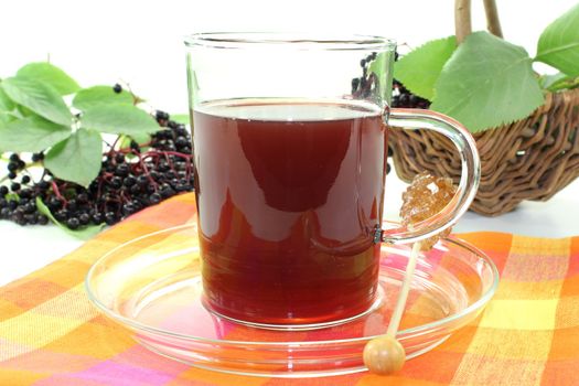 a glass of elderberry tea with fresh elderberries