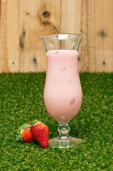 Strawberries milk shake in front of a timber wall