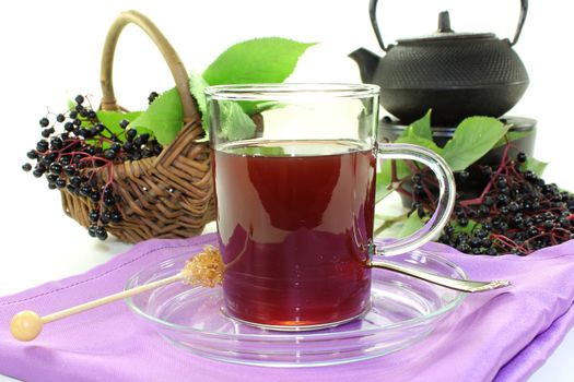 a glass of elderberry tea with fresh elderberries