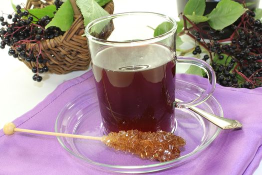 a glass of elderberry tea with fresh elderberries