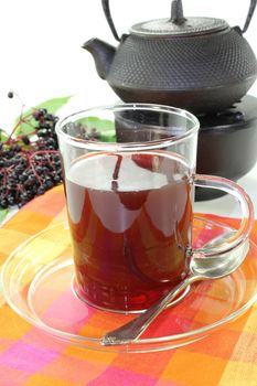 a glass of elderberry tea with fresh elderberries