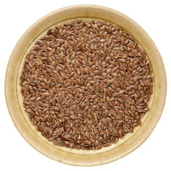 brown flax seeds in a round ceramic bowl isolated on white