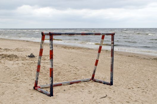 Steel metal football goal gate on sea sand. Active recreation on beach seaside.