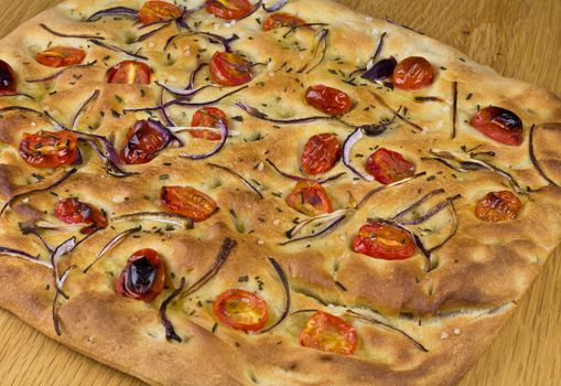 A loaf of Foccacia bread with tomatoe and onion