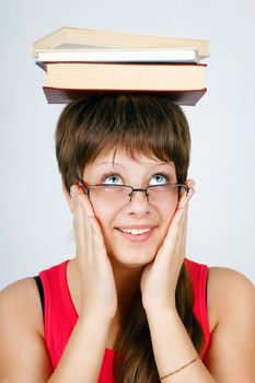 girl in glasses with the books on head on an isolated white background
