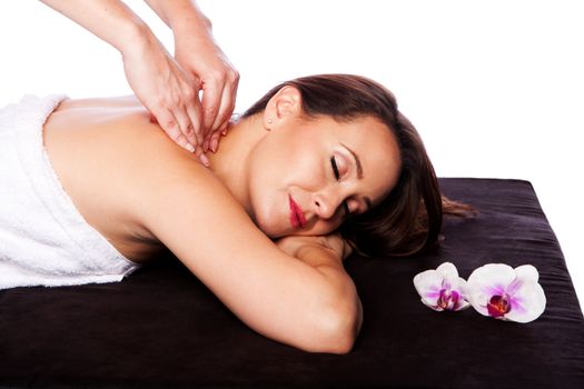 Beautiful happy peaceful sleeping woman at a spa, laying on massage table with eyes closed wearing a towel getting a neck shoulder massage, isolated.