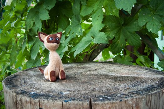 Wool curious kitten sits on a tree stump. It's handicraft. Method of creation - felting