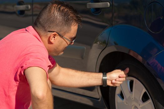 Male motorist checking the condition of a tyre