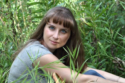 A young girl sitting in the garden in the grass

