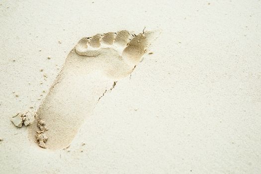 One footprint in white sand.
