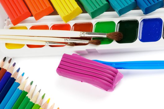 Arrangement of Clay, Paint Brushes, Color Pencils and Watercolor Paints isolated on white background