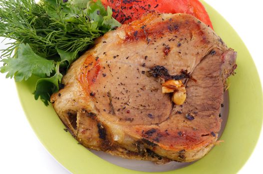 Delicious Pork Chop with Tomatoes and Greens close up on plate isolated on white background