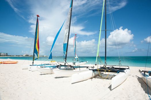 Catamarans waiting on the white sand of a Caribbean beach.